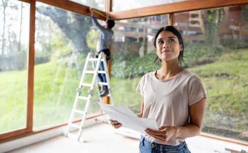 Person remodeling a house and holding designs.